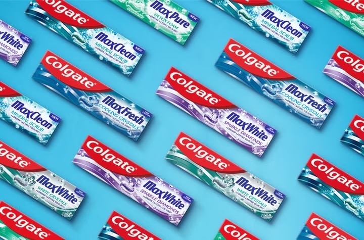 Įvairių Colgate MaxFresh, MaxWhite ir MaxClean dantų pastų pakuočių raštas mėlyname fone.